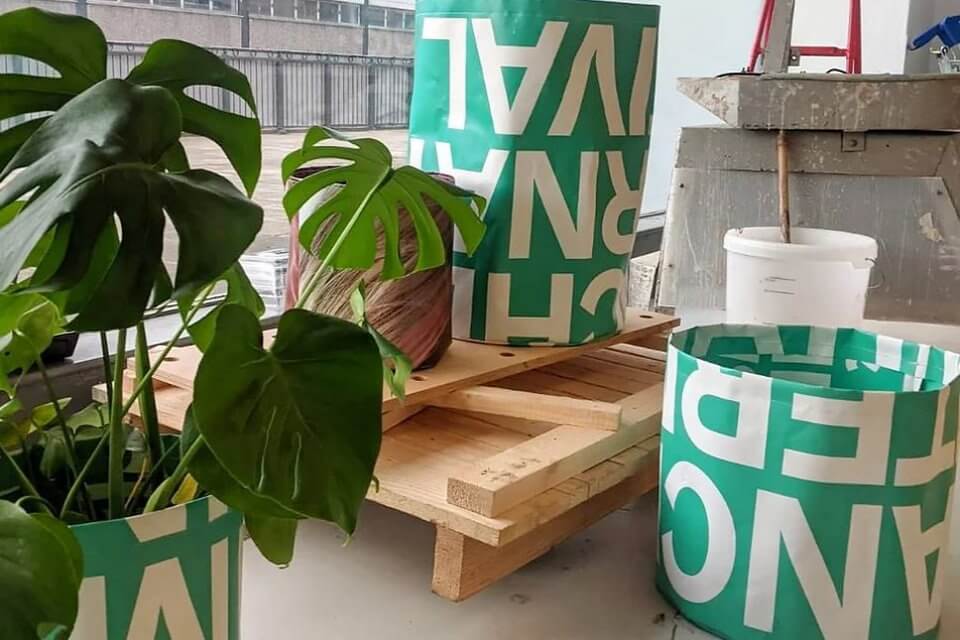 3 green plant pots made of reused plastic with white wording on one has a green plant in it