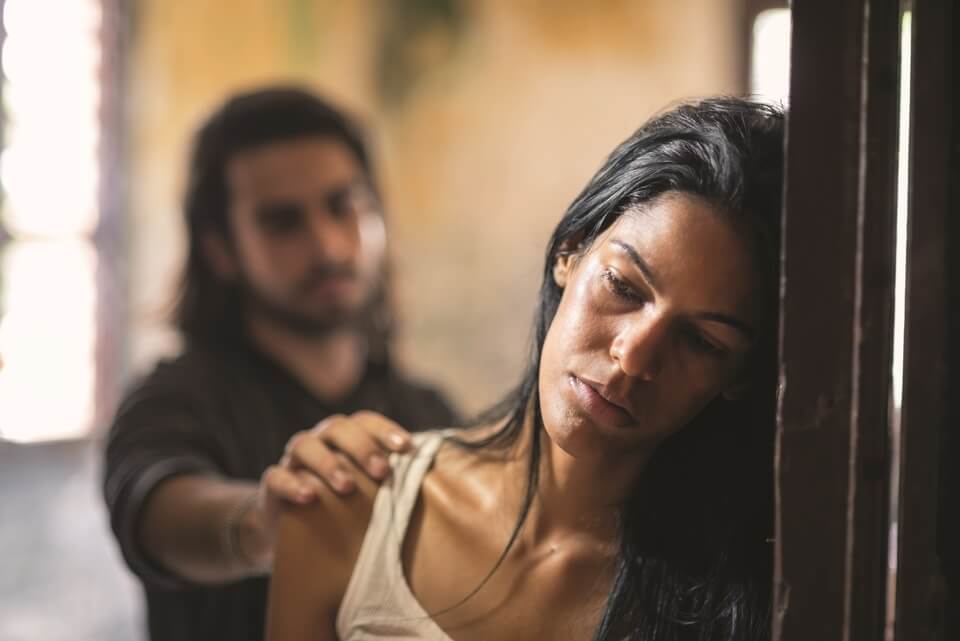 Man putting his hand on a woman's shoulder who is facing away from him