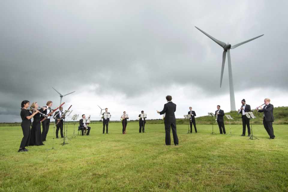 Orchestra playing beneath wind turbine