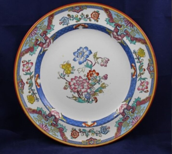 a minton plate, photographed on a dark background. Floral patterns decorate the edges and the centre