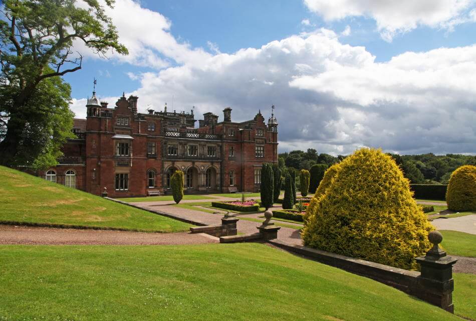 photograph of Keele Hall building in landscape with green bushes and trees in the foreground