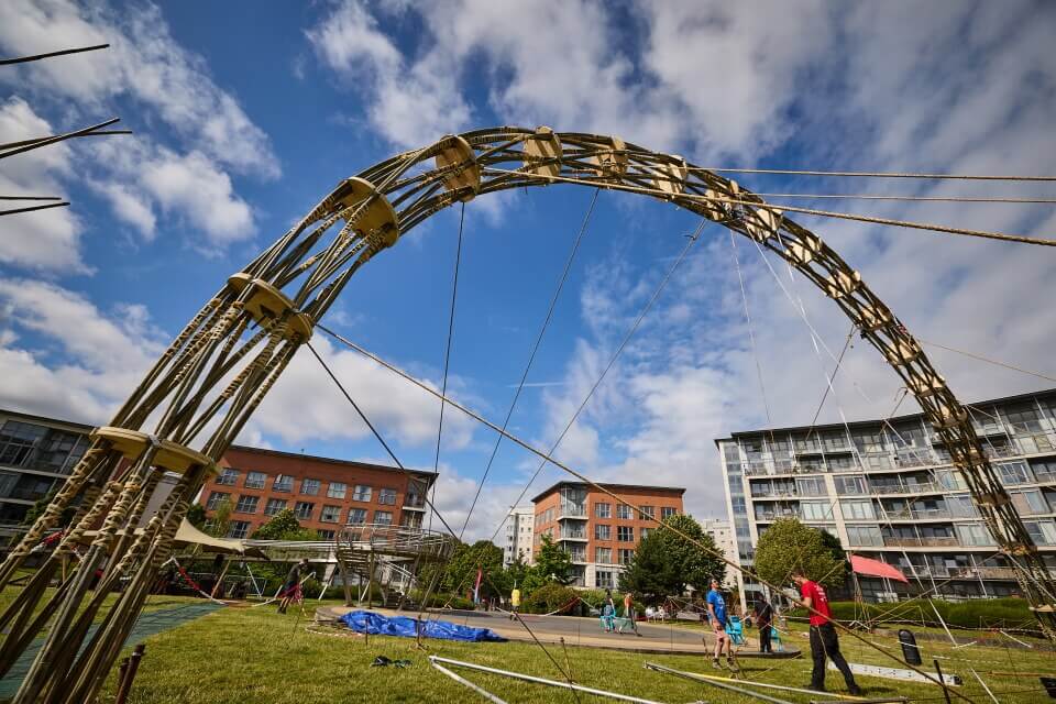 image of large bamboo arch construction on grass with blue skies and fluffy clouds 