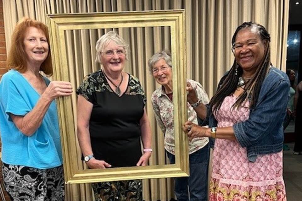 a group of adults holding a frame and smiling to the camera