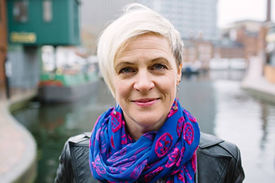 picture of Jo Bell, blue and red colourful scarf, leather jacked infront of canal