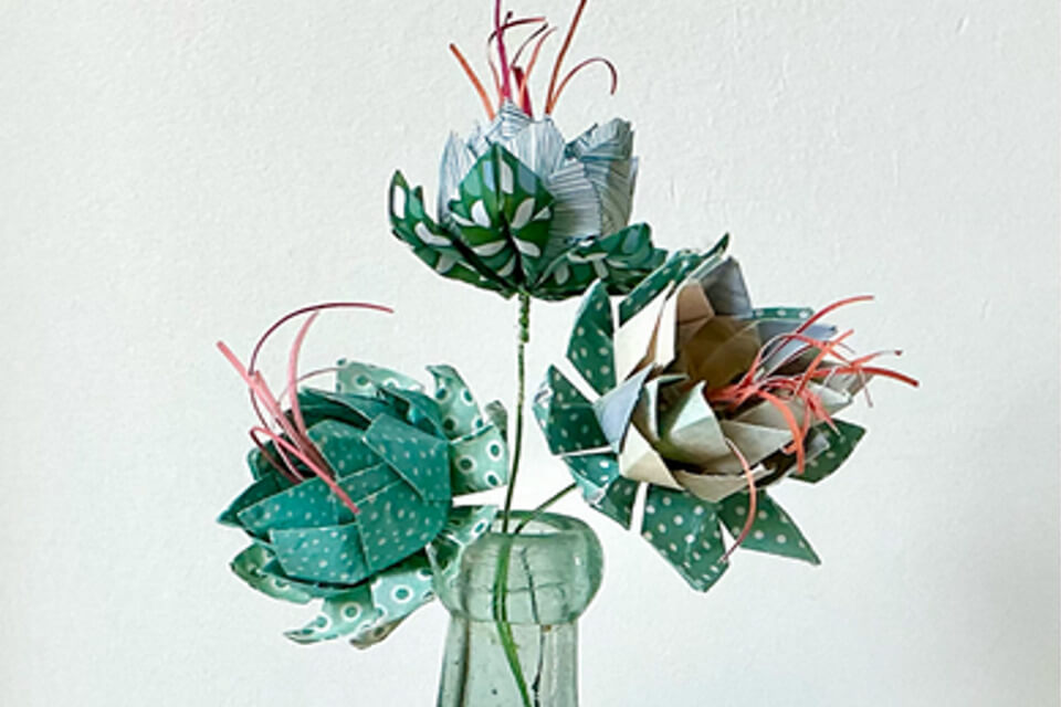 Blue and green origami flowers within a vase