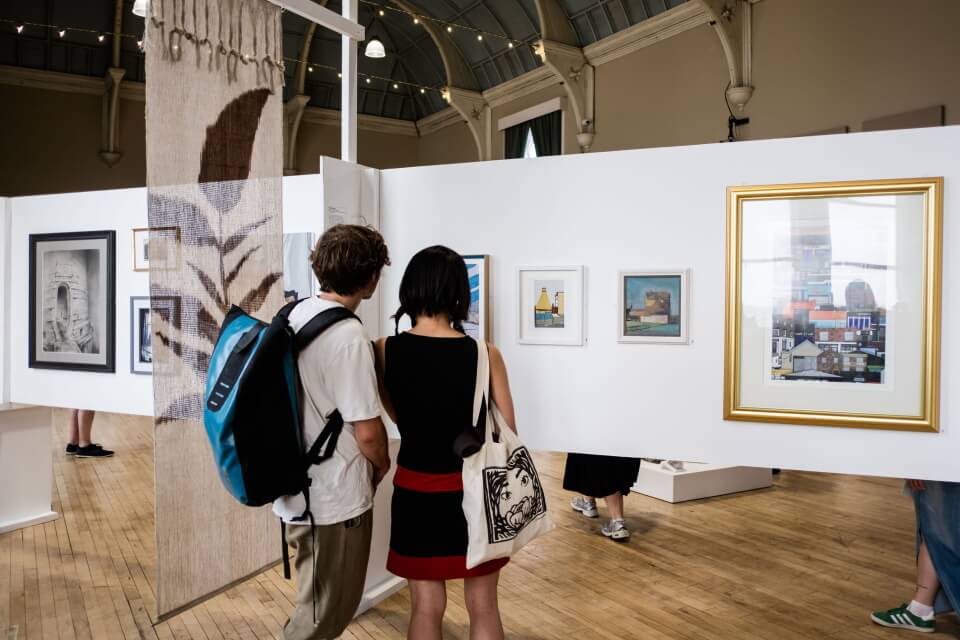 Two people viewing artwork in the Three Counties Open Art Exhibition 2025