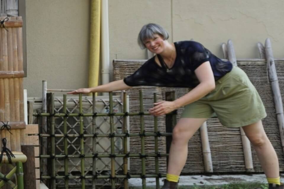 Photograph of Alice McCabe posing comically with some Bamboo cages