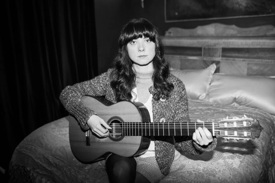 black and white photo of female seated with a guitar