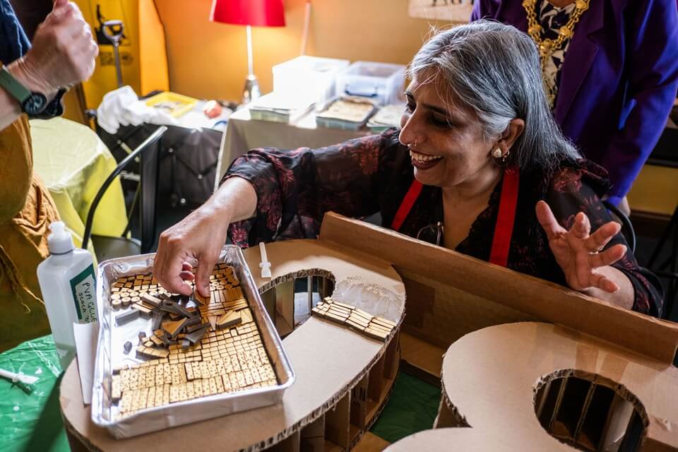 image of lady adding mosaic pieces to a template and smiling