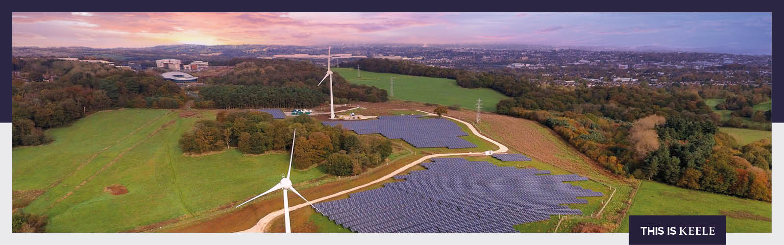 Drone photo of the Low Carbon Energy Generation Park during sunset, showing a field of solar panels and two wind turbines, at Keele University