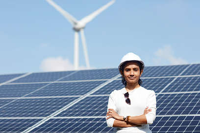 Student stood in front of solar panels on a sunny day wearing a hard hat