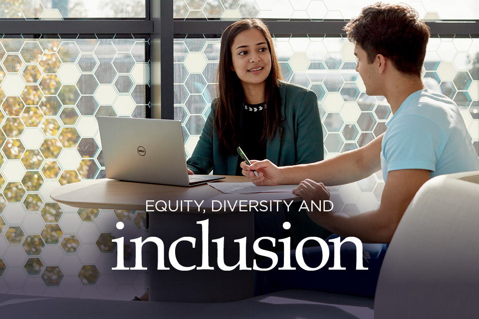 Two people smiling while chatting in a work setting at Keele University