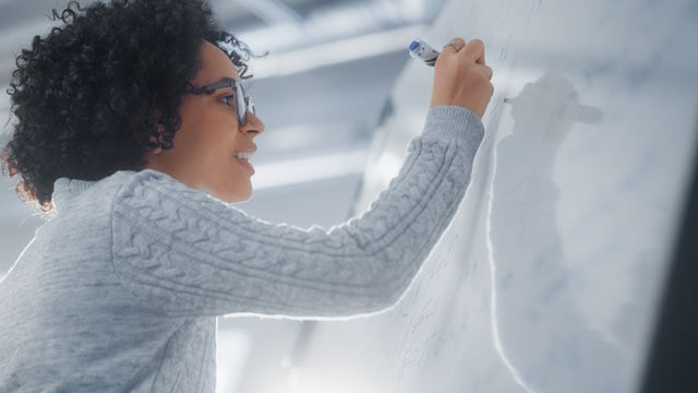 A person writing on a white board