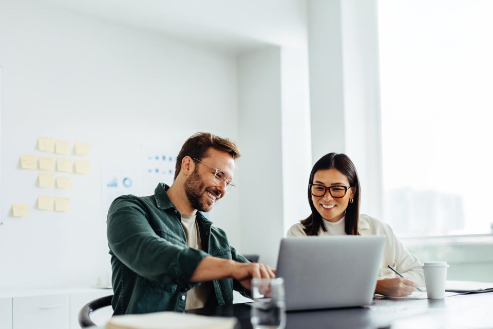 Two people smiling while looking at a laptop screen