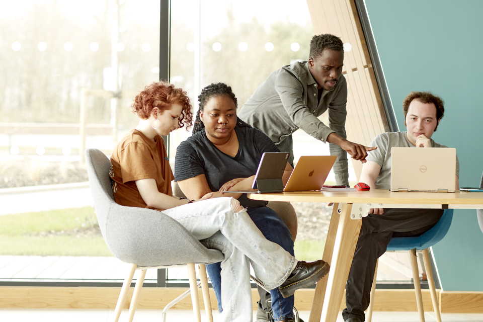 Students talking whilst sat around laptop computers