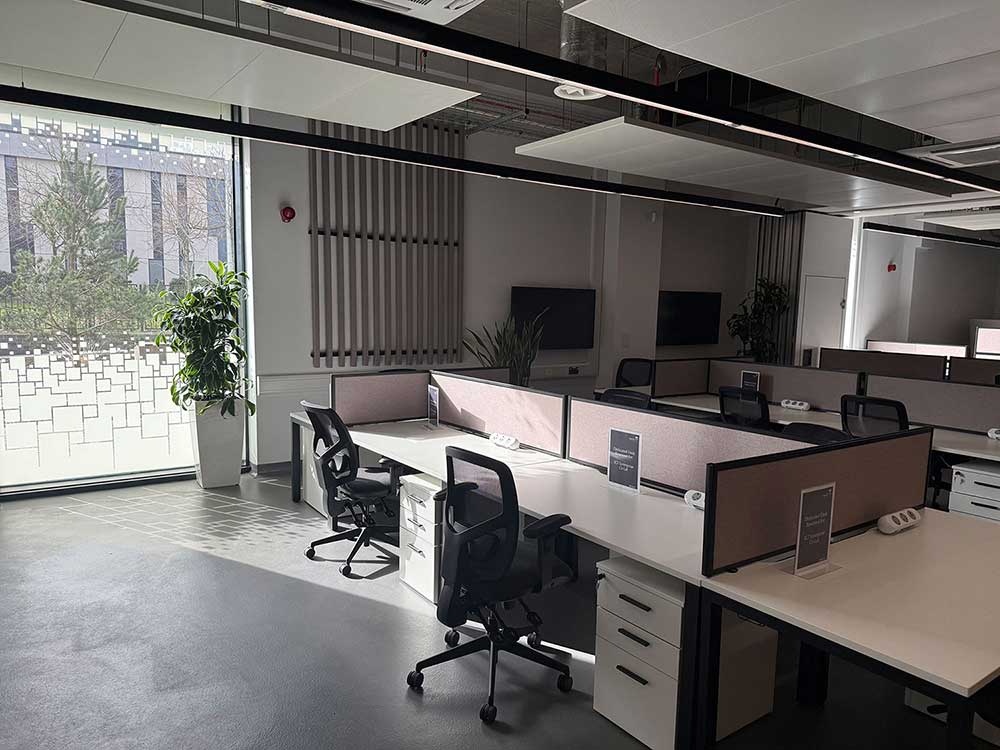 Photograph of the Keele University coworking space, foreground desks with chairs, background soft seating and bookshelves