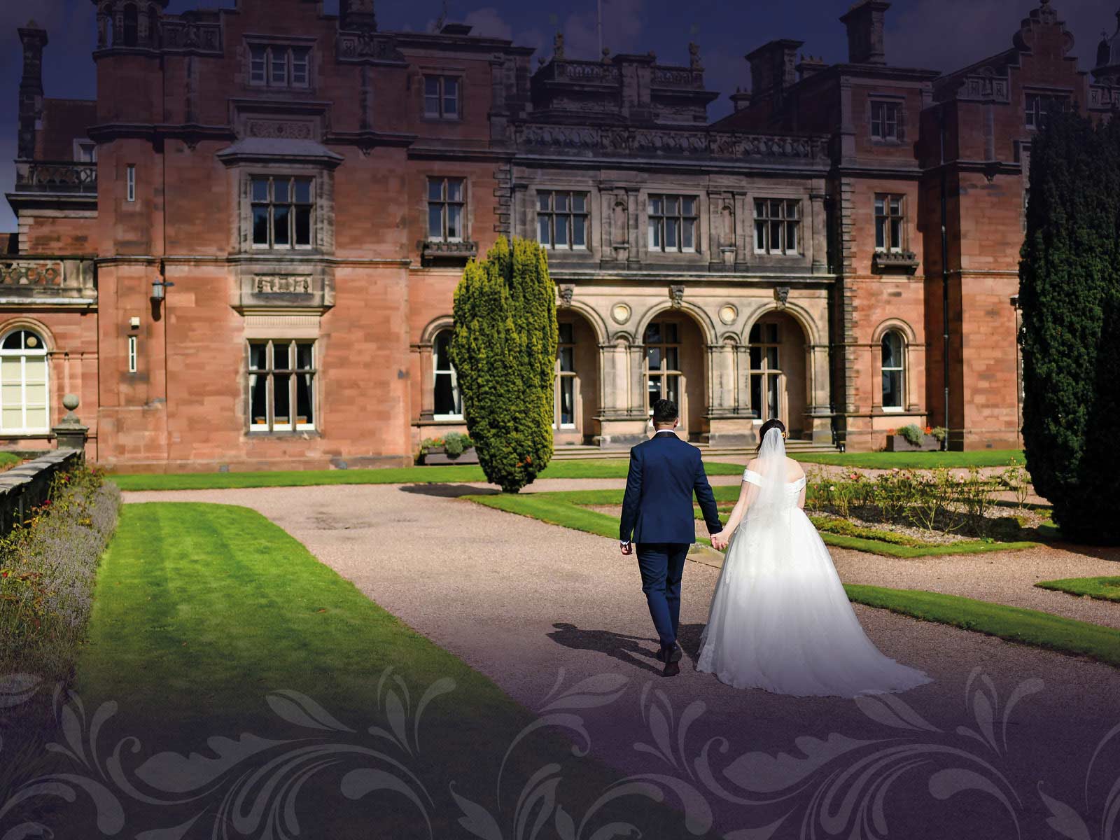 Newly married couple walking towards Keele Hall