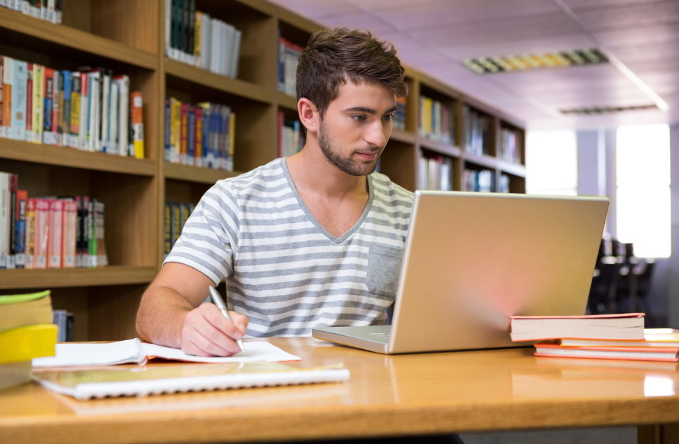 Student consulting an ejournal on a laptop, while sitting in the library