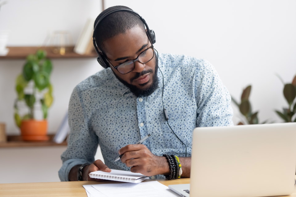 man working at a laptop, wearing headphones