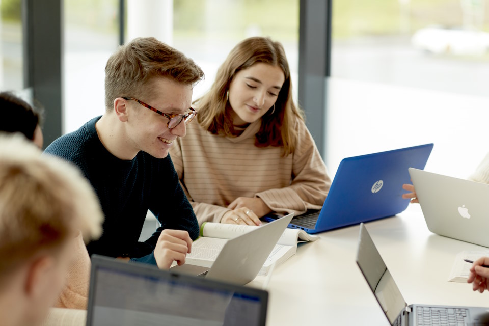 group of students working on laptops at a desk