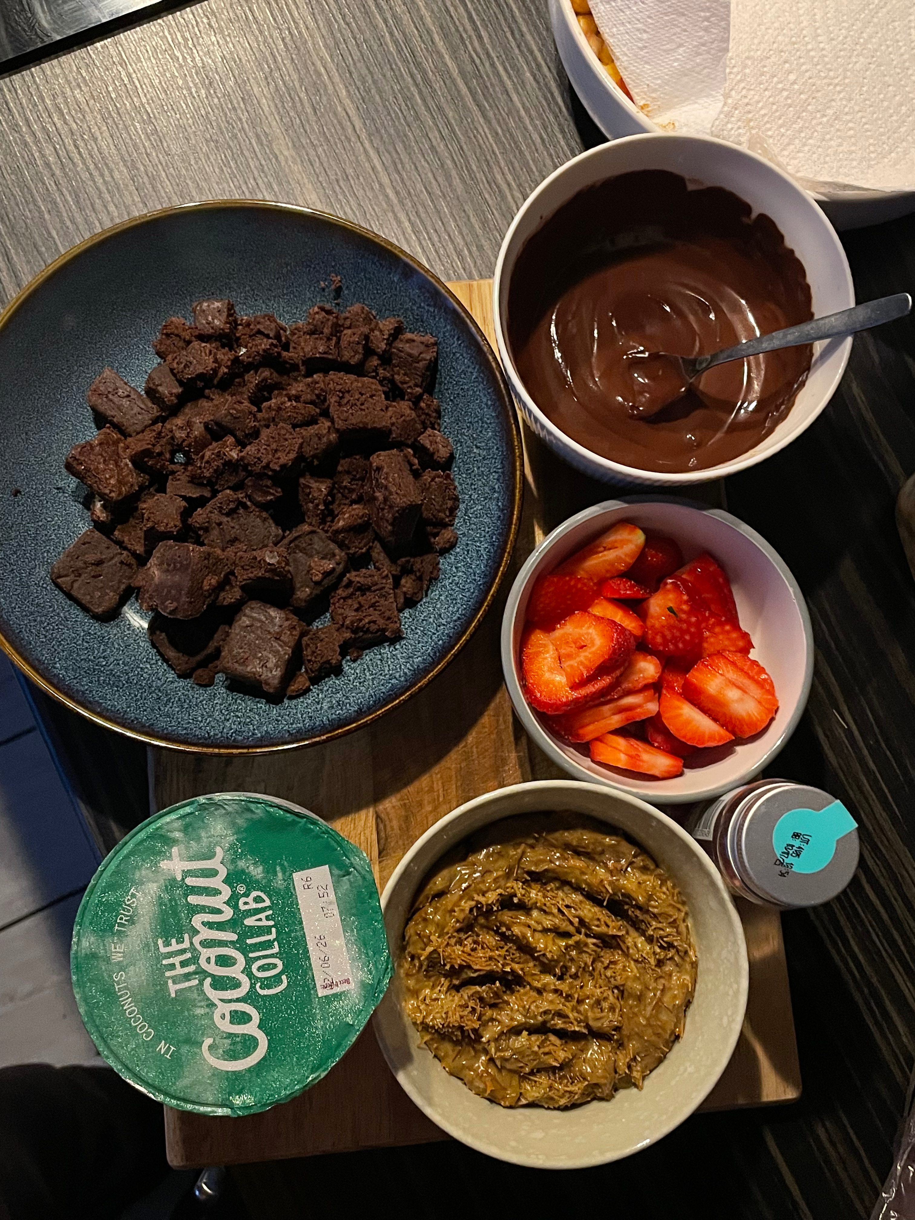 5 bowls displaying brownies, strawberries, melted chocolate, pistachio cream and yoghurt