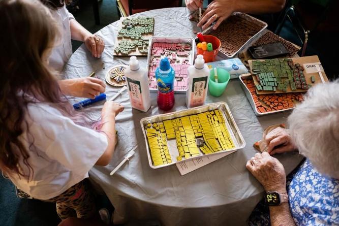 People seated around a table crafting with mosaic tiles