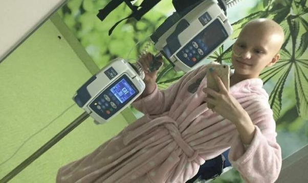 A young woman undergoing cancer treatment takes a selfie in hospital.