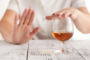 An anonymous person putting their hand over a glass of alcohol and using their other hand to make a no gesture
