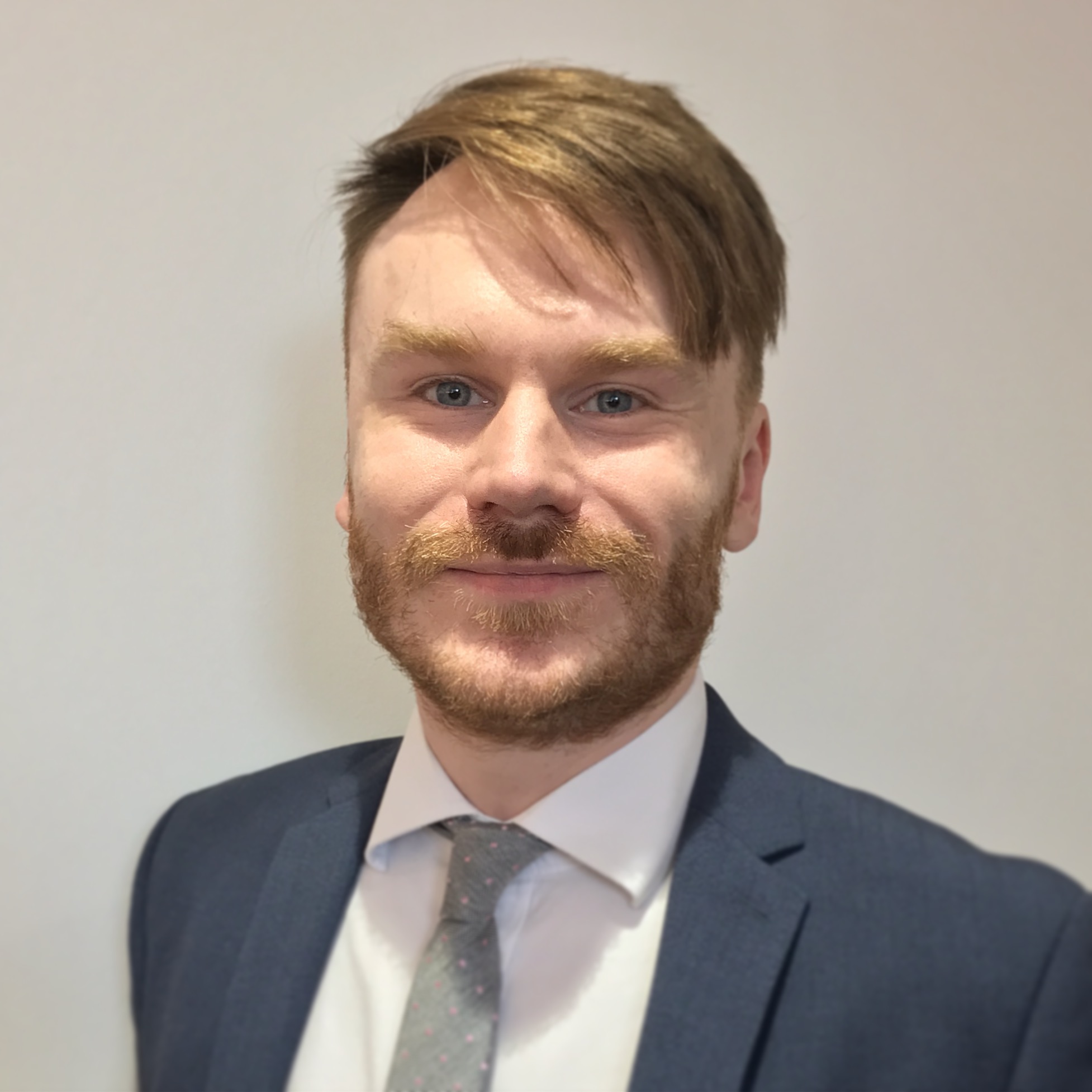 Smiling headshot of Ewart Hodge in blazer, shirt and tie 