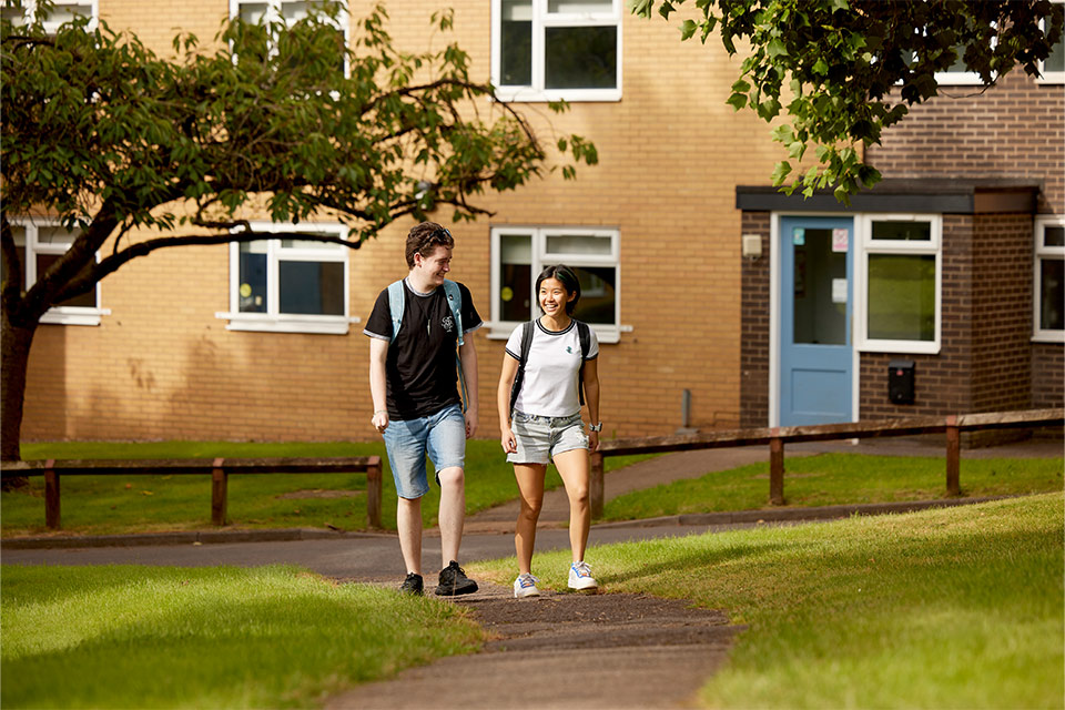 Two students laughing and walking way from campus accommodation.