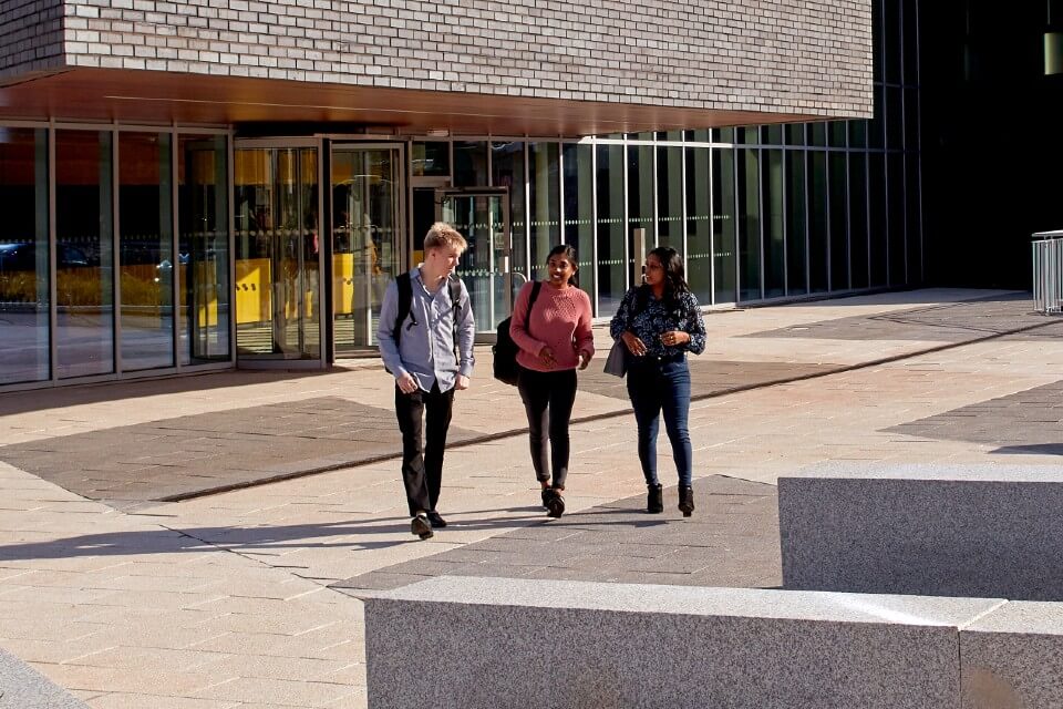 Three students walking in front of a building