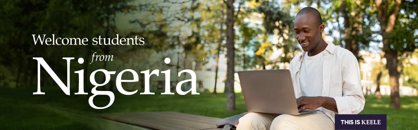 Student sitting and smiling, looking at laptop.