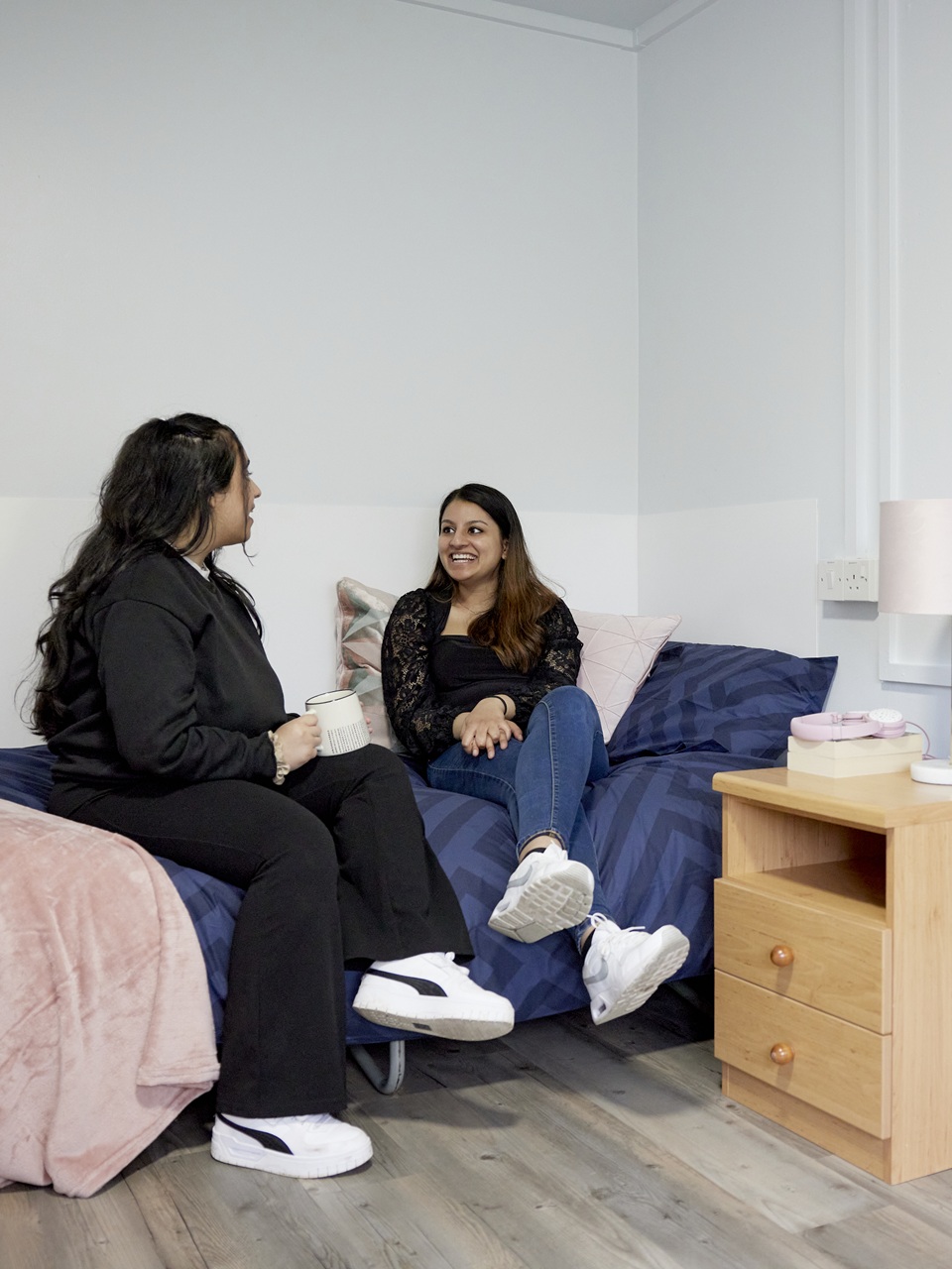 Two students sitting on a bed in Keele accommodation.