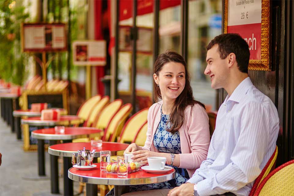 Two people sat together smiling, drinking coffee