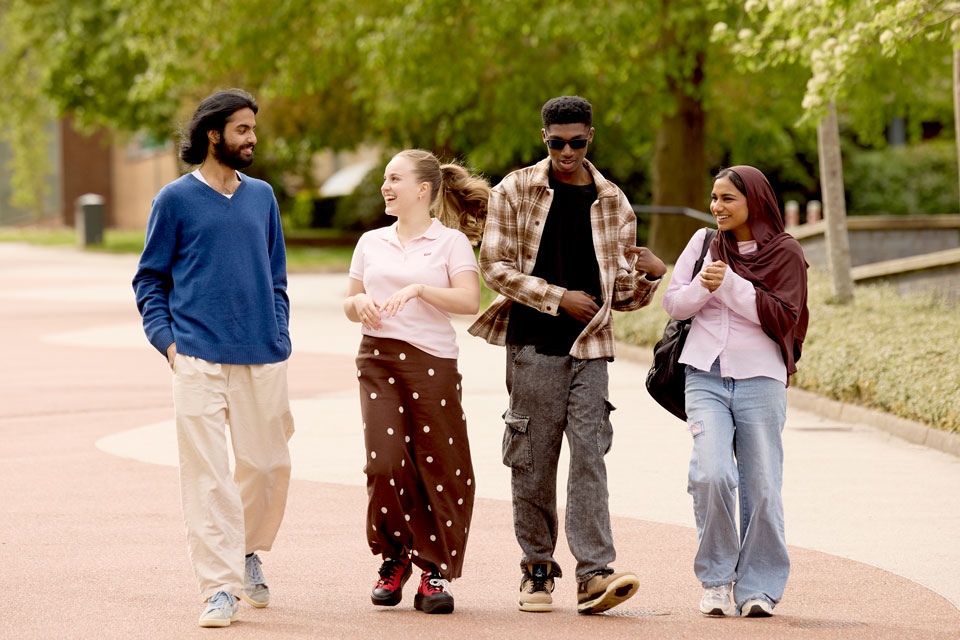 Group of four undergraduate students walk together on Central Drive on Keele Campus.