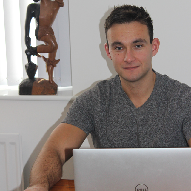 male smiling in front of a laptop 