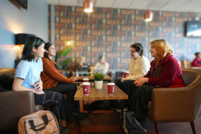 A group of students chatting and having coffee in a cafe on Keele University campus.