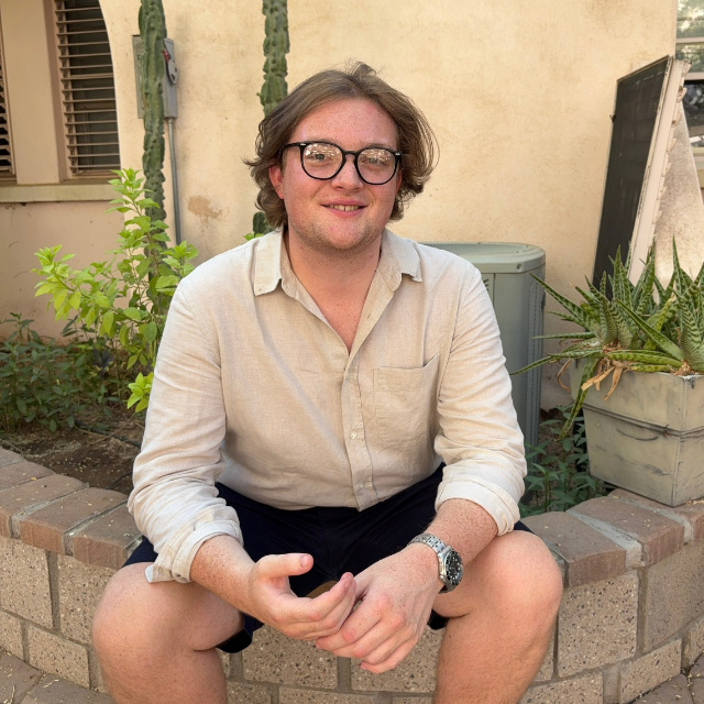 Man sitting facing camera with black rimmed glasses
