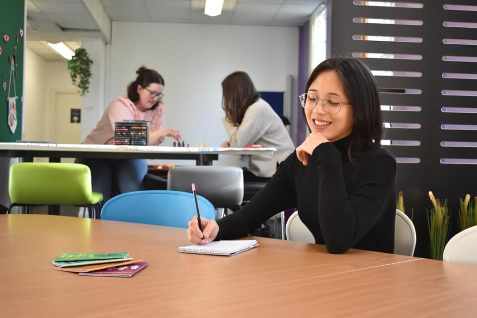Student smiling, sitting in campus building