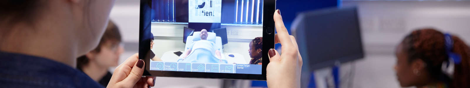 A student from the School of Allied Health Professions and Pharmacy with a tablet and looking at a virtual patient.