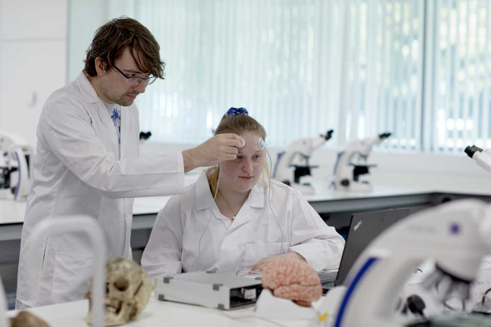 Male student placing brain sensors on a female student in the David Attenborough Lab at Keele.