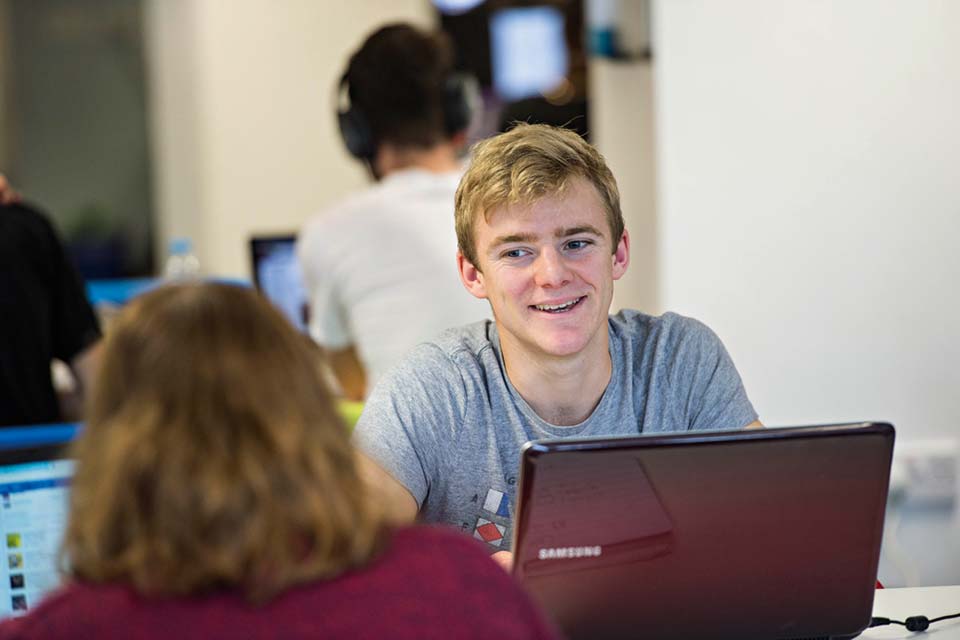 Student sitting with laptop smiling