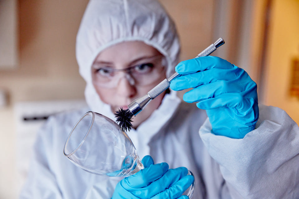 Forensic Biology student wearing forensics suit looking at glass