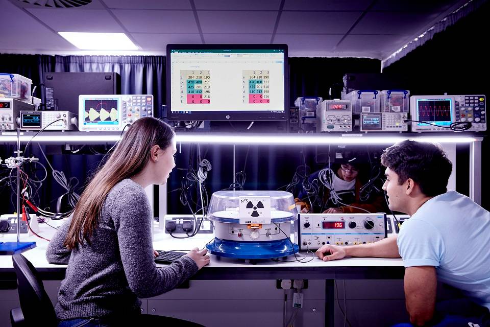 Physics students looking at equipment in laboratory