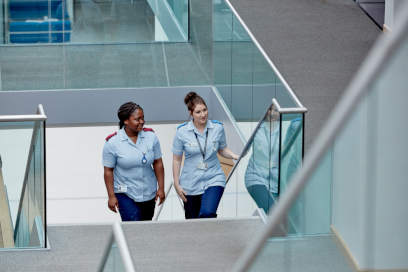 Two female nursing students walking up a flight of stairs at the Clinical Education Centre.