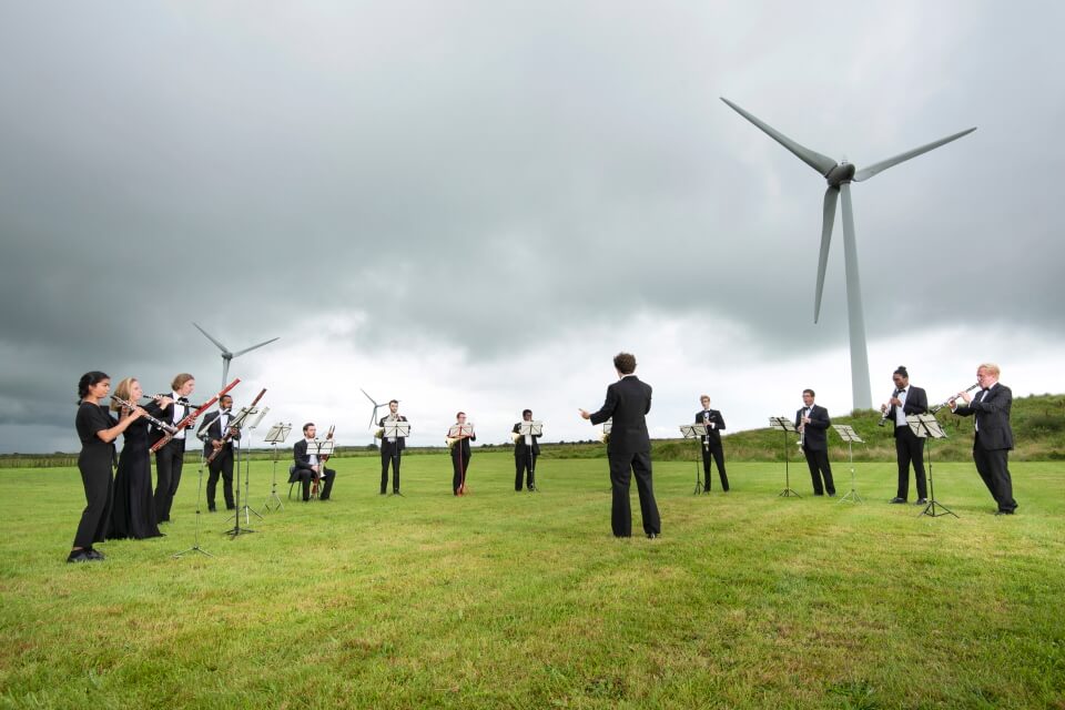 image of orchestra performing under wind turbines