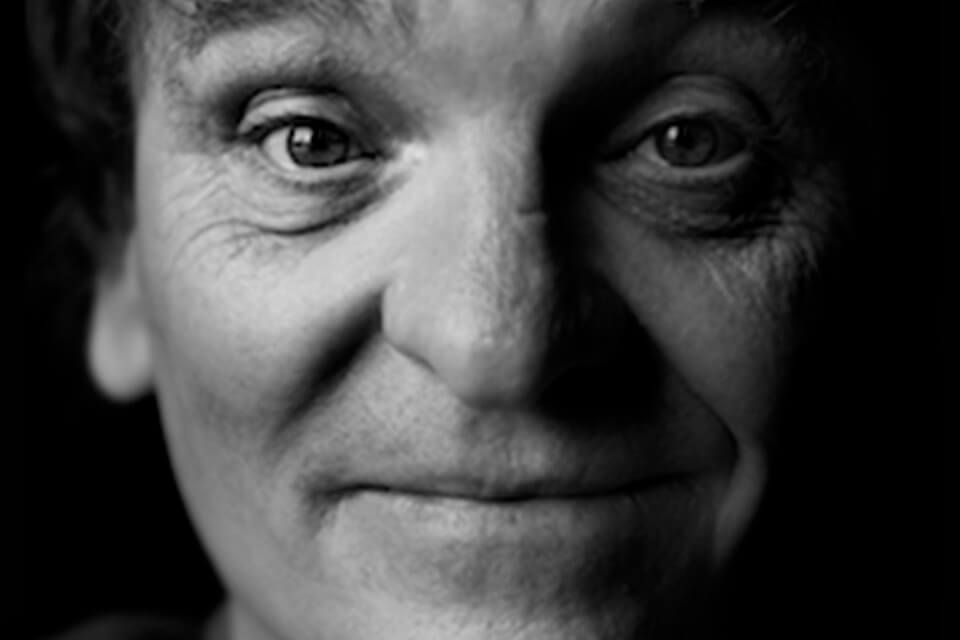 black and white photo of a mans face smiling looking directly at viewer