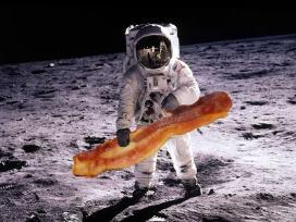 A person in a space suit on the surface of the moon with an oversized piece of bacon edited into their hand